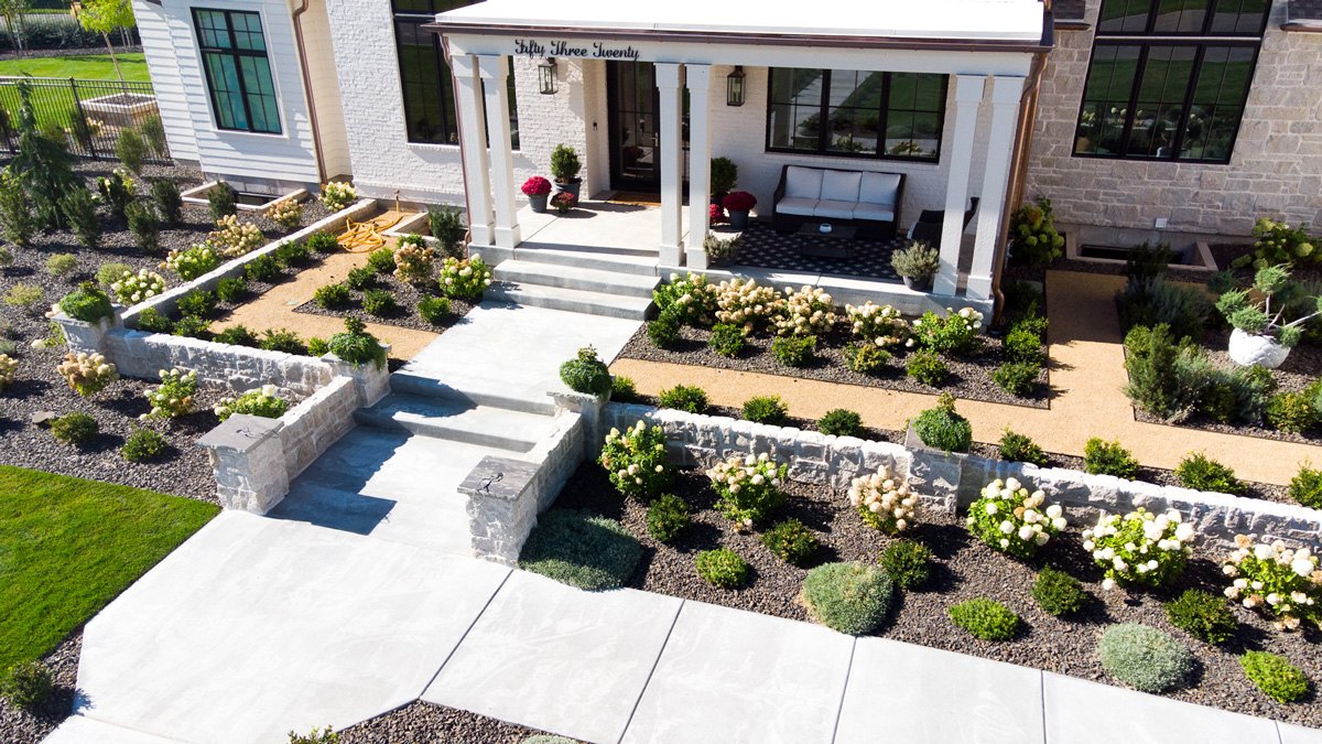 Aerial view of a completed J&F landscape with paver patio, lawn, and planting beds